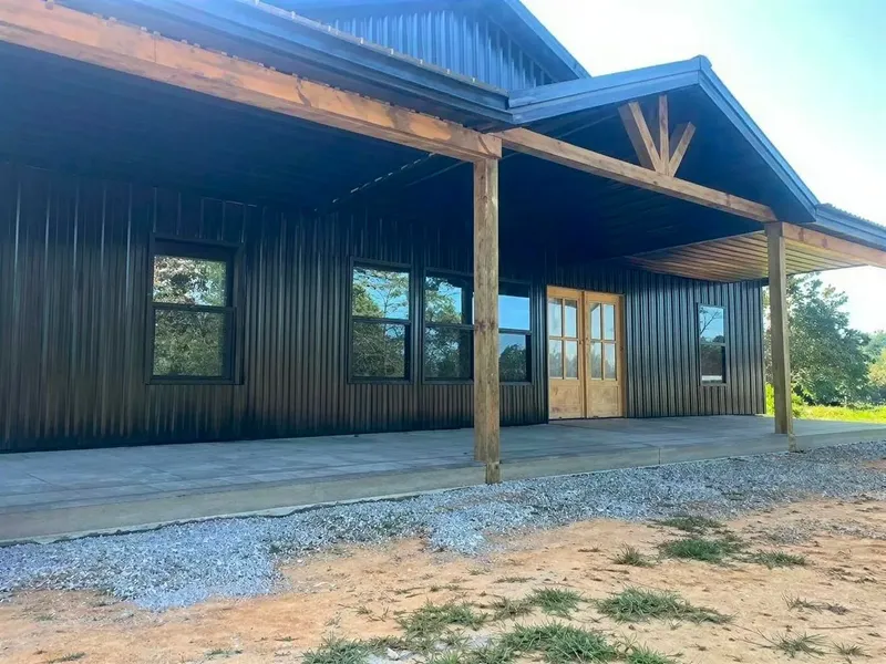 Close view of a barndominium covered porch with timber posts and a gabled entrance