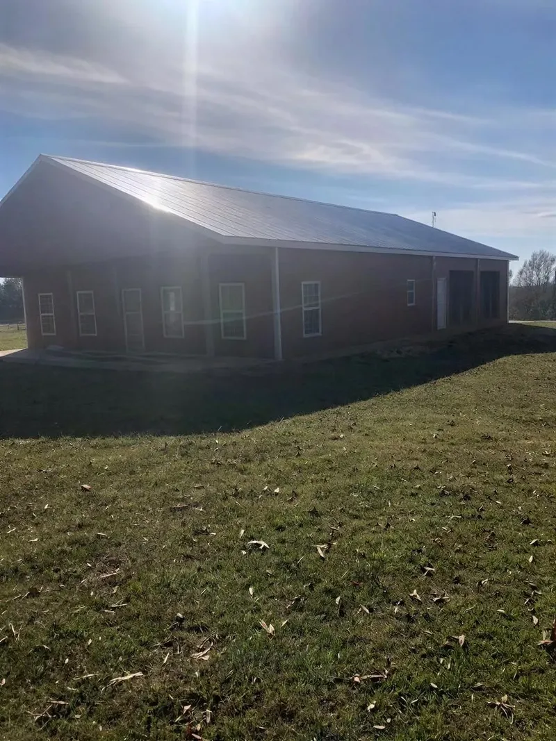 Barndominium exterior with a long covered porch in afternoon sunlight