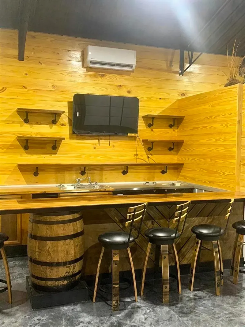 Wood-paneled barndominium lounge with a television, shelving, and barrel-style bar seating