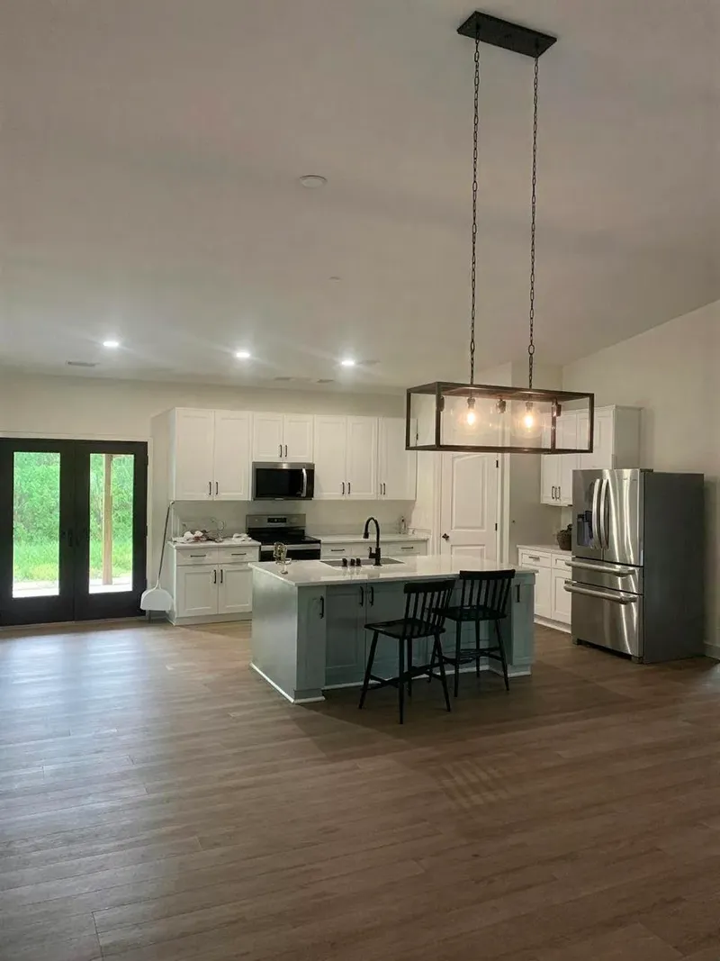 Open-plan barndominium kitchen with an island, pendant lights, and wood-look flooring