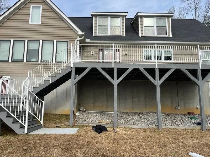 Elevated deck with white railings and a staircase beside a home