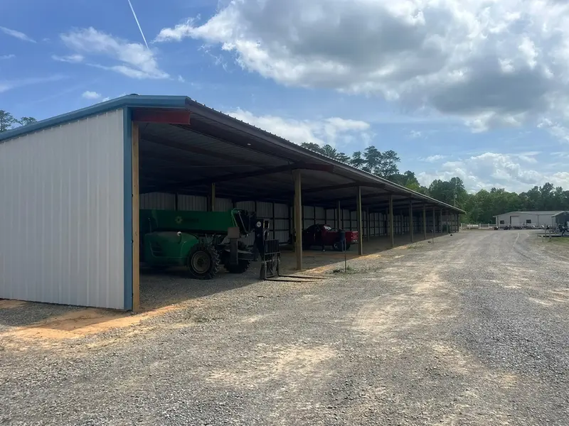 Open-sided metal equipment shelter with farm machinery inside