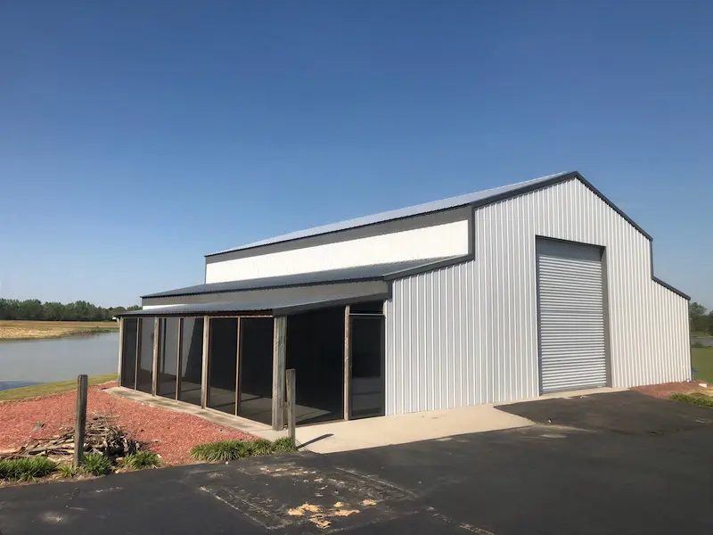 Light metal building with a covered side porch and tall garage door