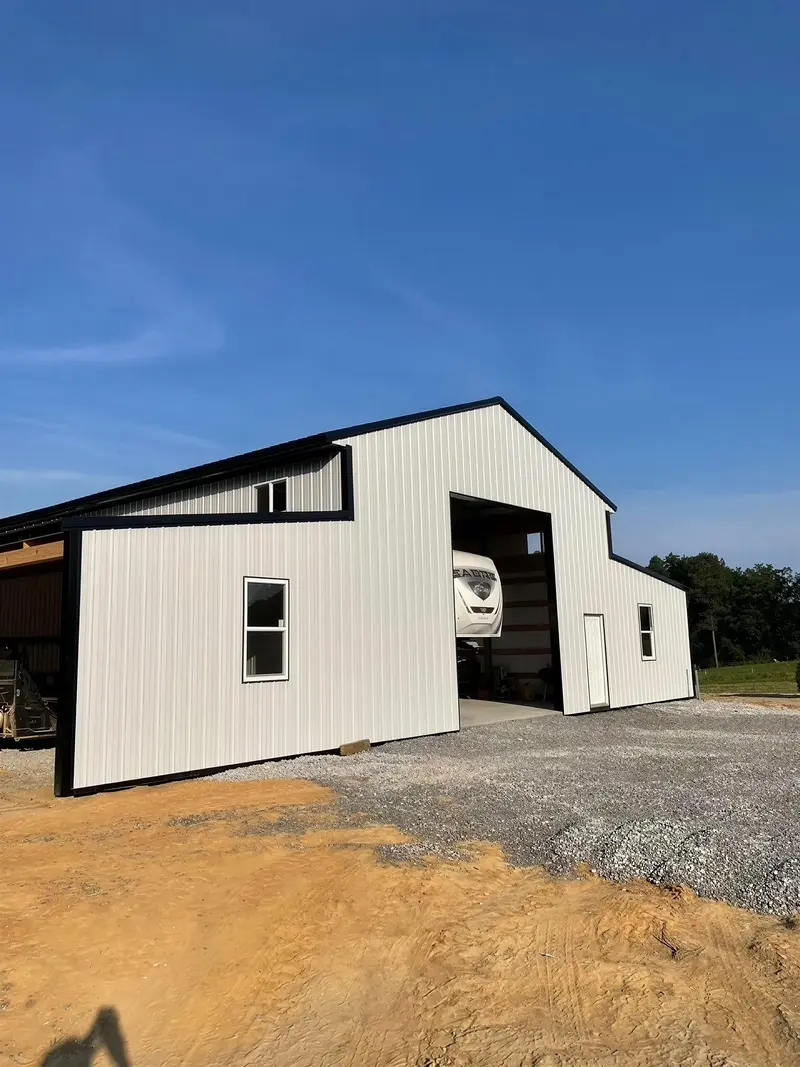 Light metal building with dark trim and an adjoining garage